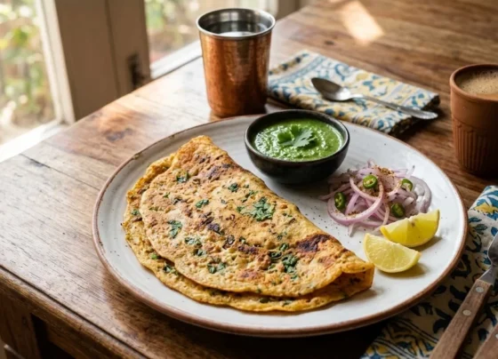 Golden brown Moong Dal Chilla served with green mint chutney on a white ceramic plate.